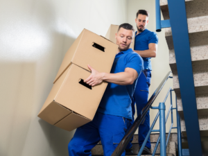 two professional movers moving boxes in a Houston apartment stairwell